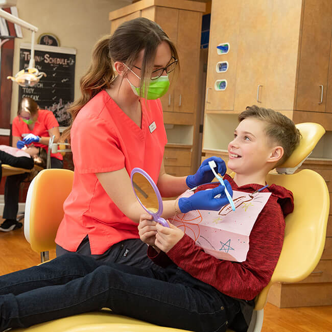 A boy sitting in the chair as a team member cares for his smile